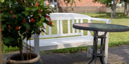 Billede af en hvid bænk, et bord og en blomst på Solgaven Næstved