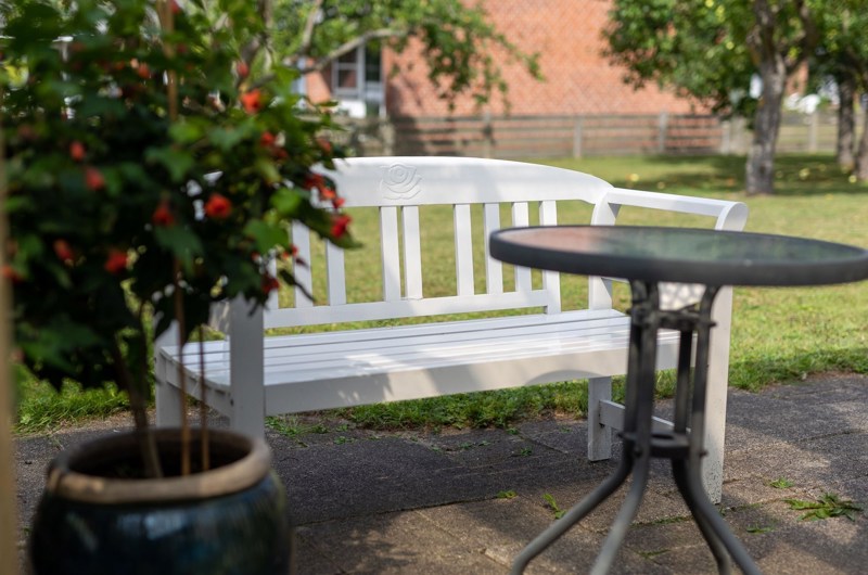 Billede af en hvid bænk, et bord og en blomst på Solgaven Næstved