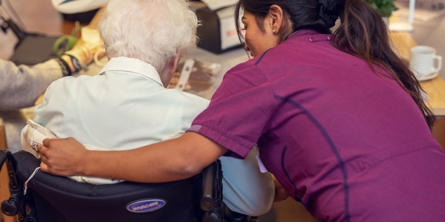Medarbejder på Solgaven Næstved viser omsorg ved at holde sin arm om en beboer i kørestol