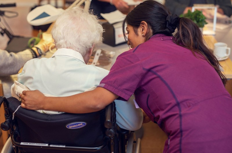 Medarbejder på Solgaven Næstved viser omsorg ved at holde sin arm om en beboer i kørestol