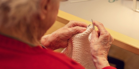 En beboer der sidder ved et bord og strikker