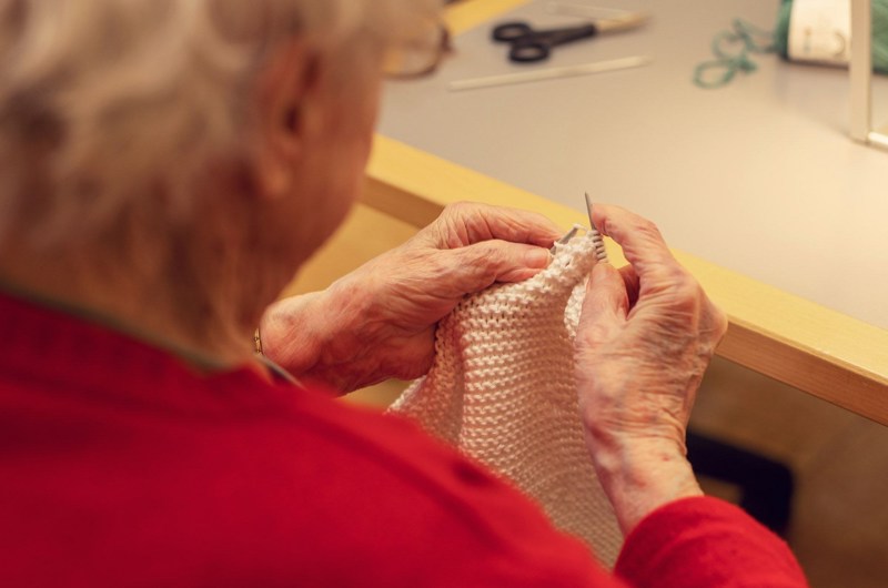 En beboer der sidder ved et bord og strikker